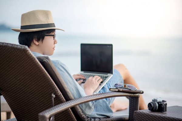 man siting on beach chair with laptop
